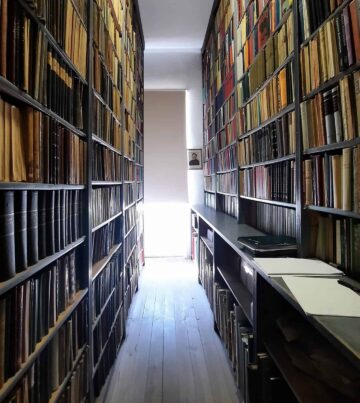 Ein langer Flur mit vielen Büchern auf Regalen. {{brizy_dc_image_alt imageSrc=