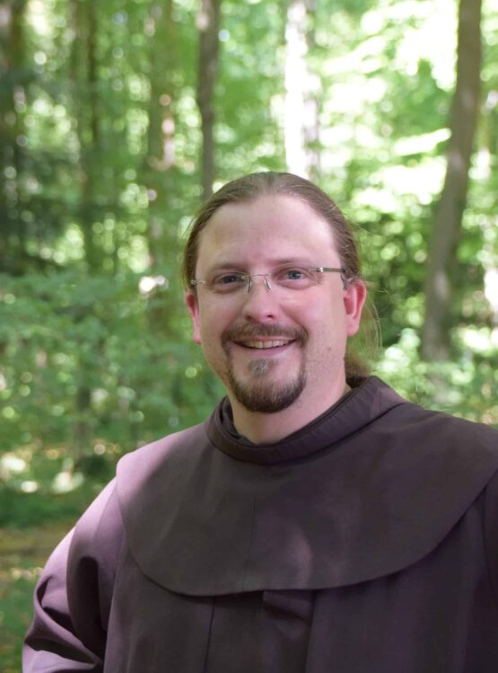 Ein Mann in einem braunen Gewand steht im Wald.