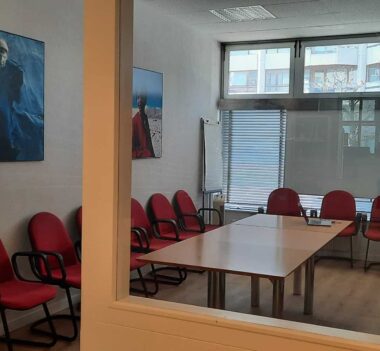 Ein Konferenzraum mit roten Stühlen und einem Gemälde an der Wand.