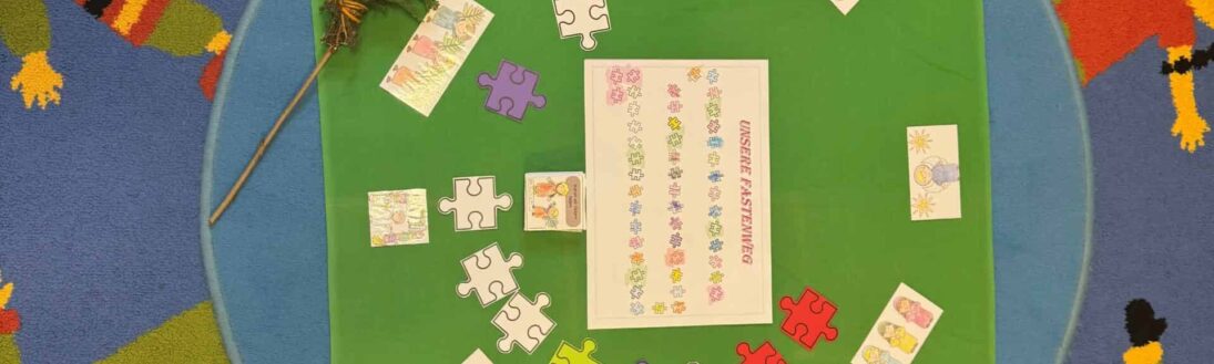Eine grüne Matte mit Puzzleteilen, Karten und einem blättrigen Zweig liegt auf einem blauen Teppich, der mit Cartoon-Kindern verziert ist.
