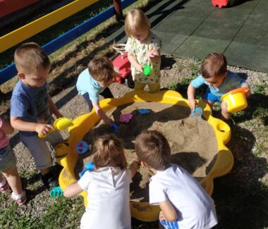 Eine Gruppe Kinder spielt in einem Sandkasten.